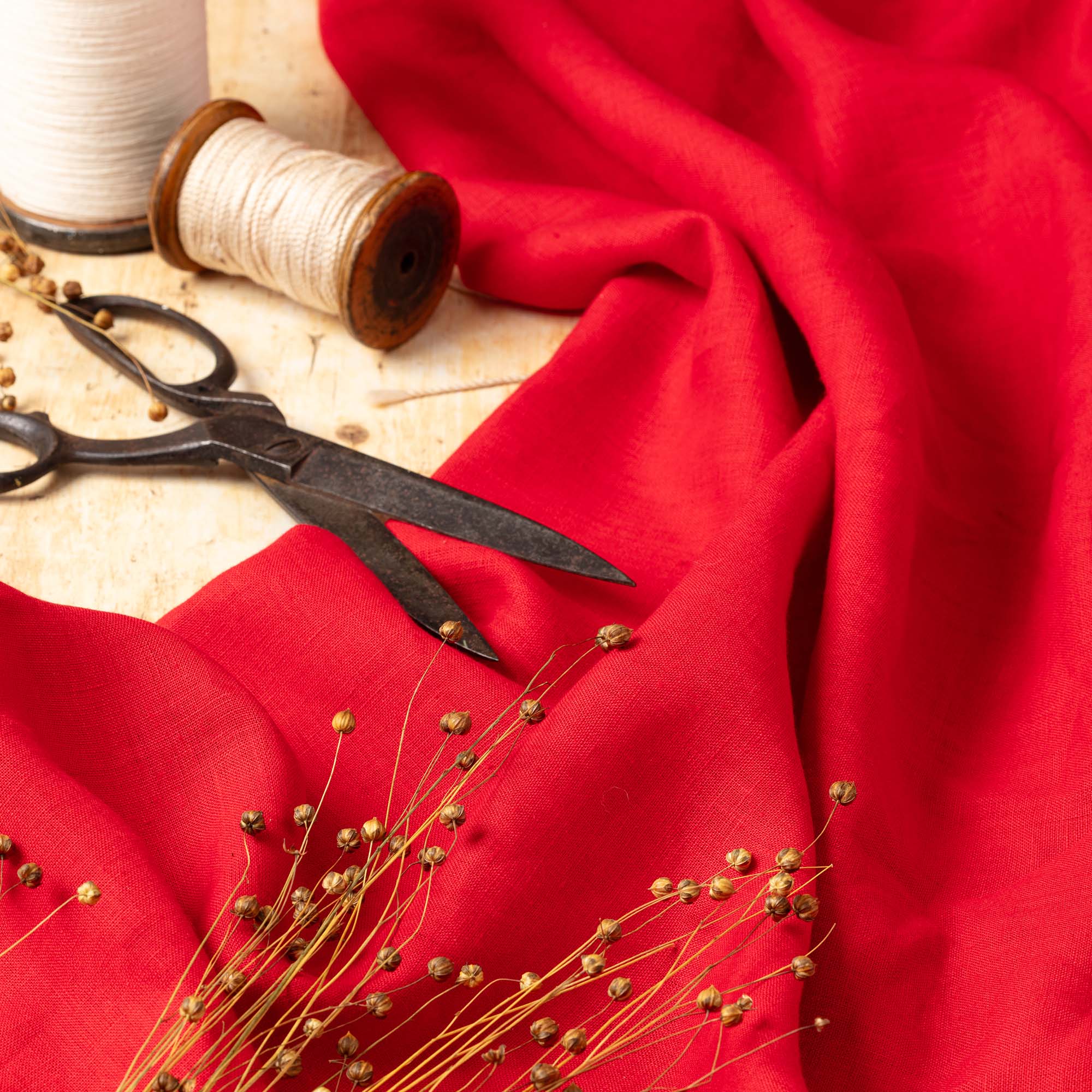 Bright Red linen fabric, ready to cut, with scissors, thread bobbins and flowers