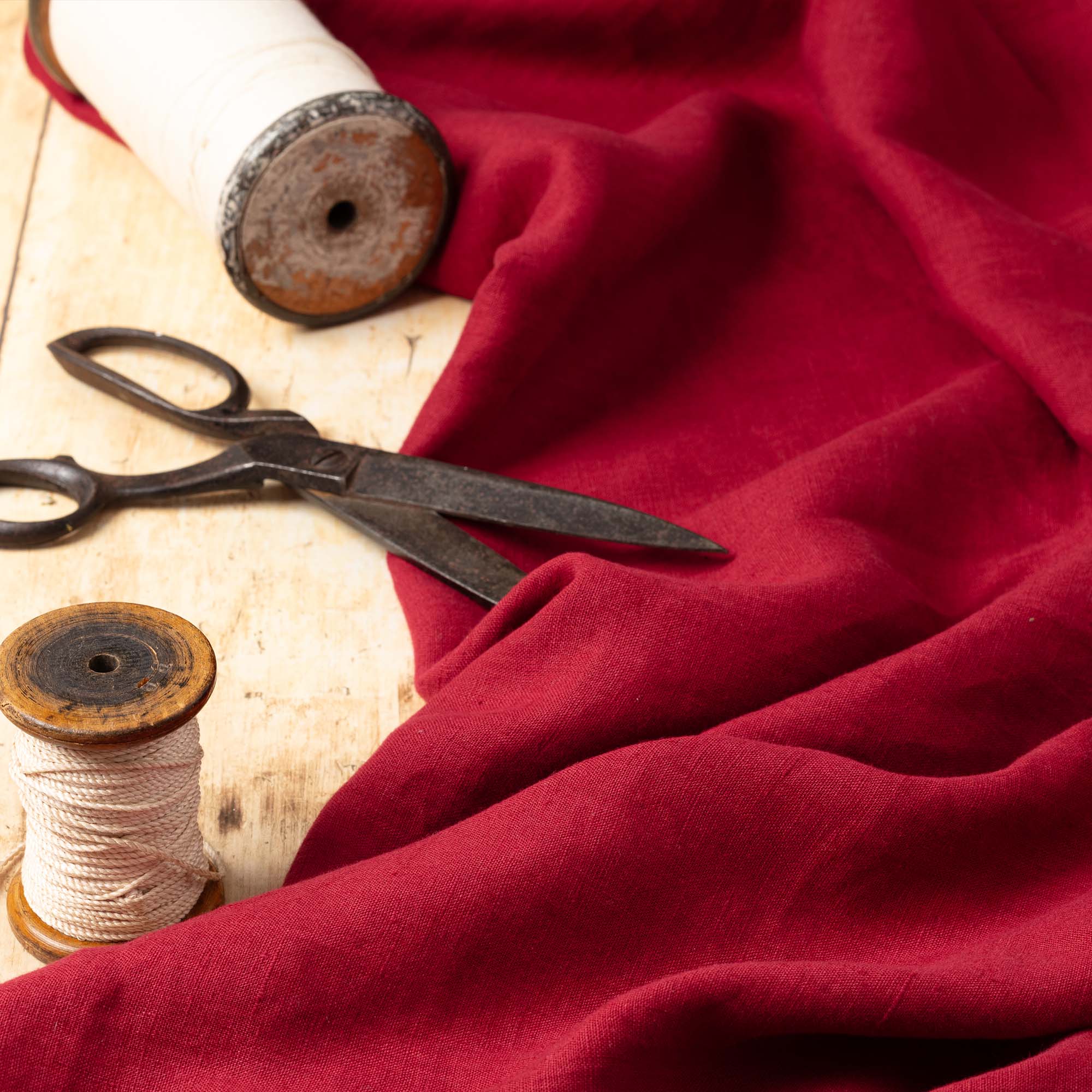 Burgundy linen fabric, ready to cut, with scissors, thread bobbins and flowers