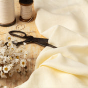 Buttercream linen fabric, ready to cut, with scissors, thread bobbins and flowers