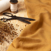 Caramel linen fabric, ready to cut, with scissors, thread bobbins and flowers