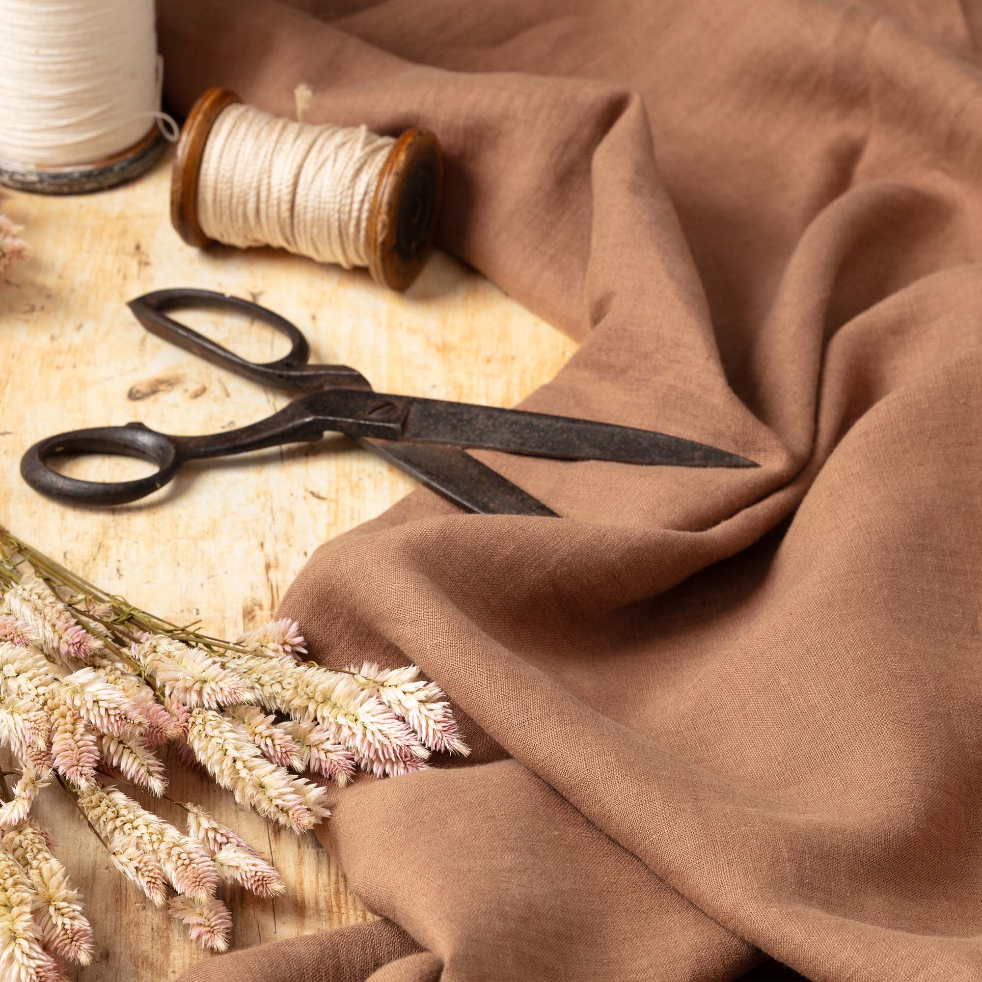 Cinnamon linen fabric, ready to cut, with scissors, thread bobbins and flowers