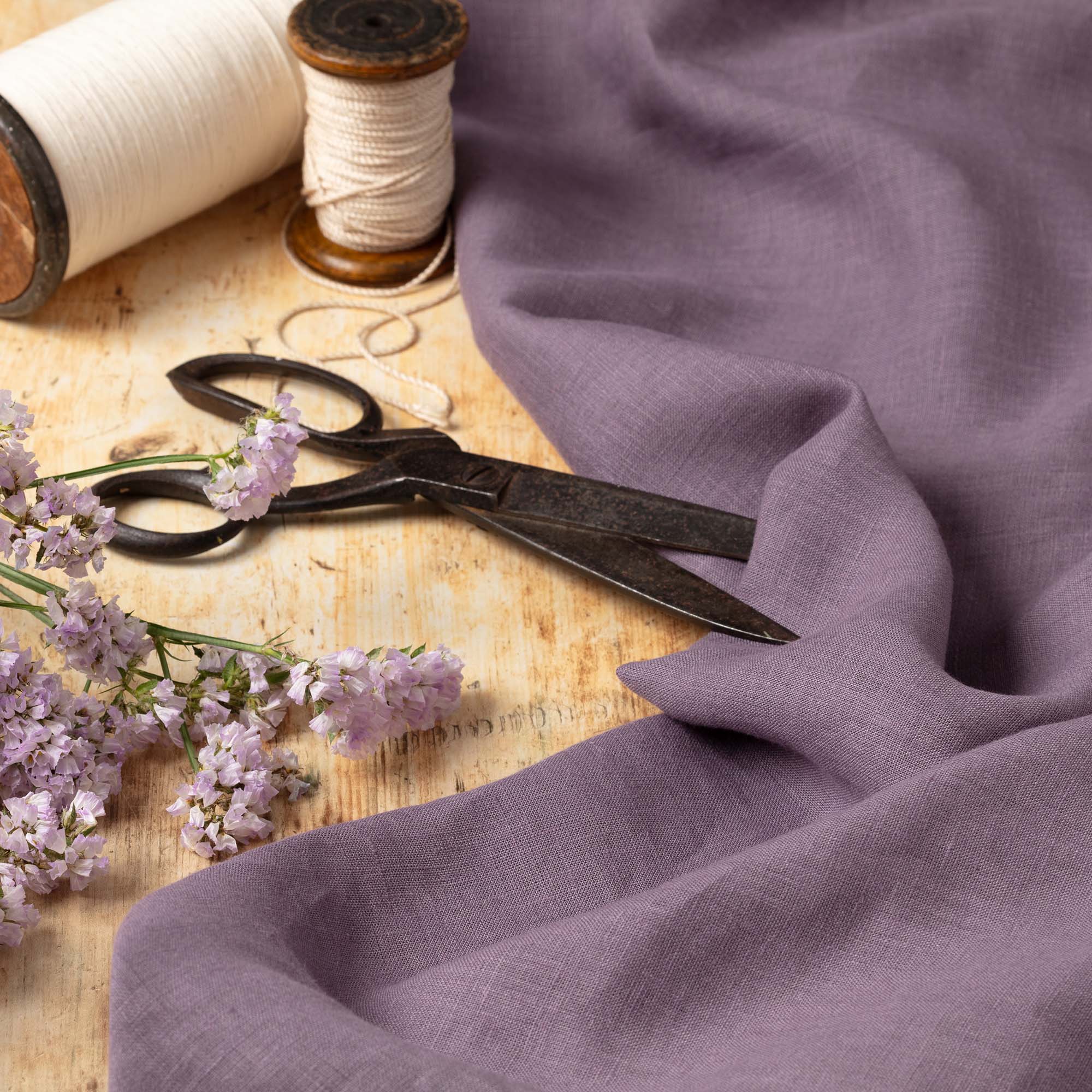 Dusty Purple linen fabric, ready to cut, with scissors, thread bobbins and flowers