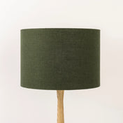 An avocado dark green lampshade on a wooden lamp base, with a textured weave design, photographed against a white background.