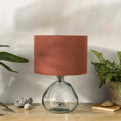Terracotta linen lampshade with recycled glass base on wooden desk with plants
