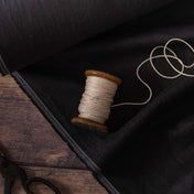 Black linen fabric, ready to cut, with scissors and thread bobbins