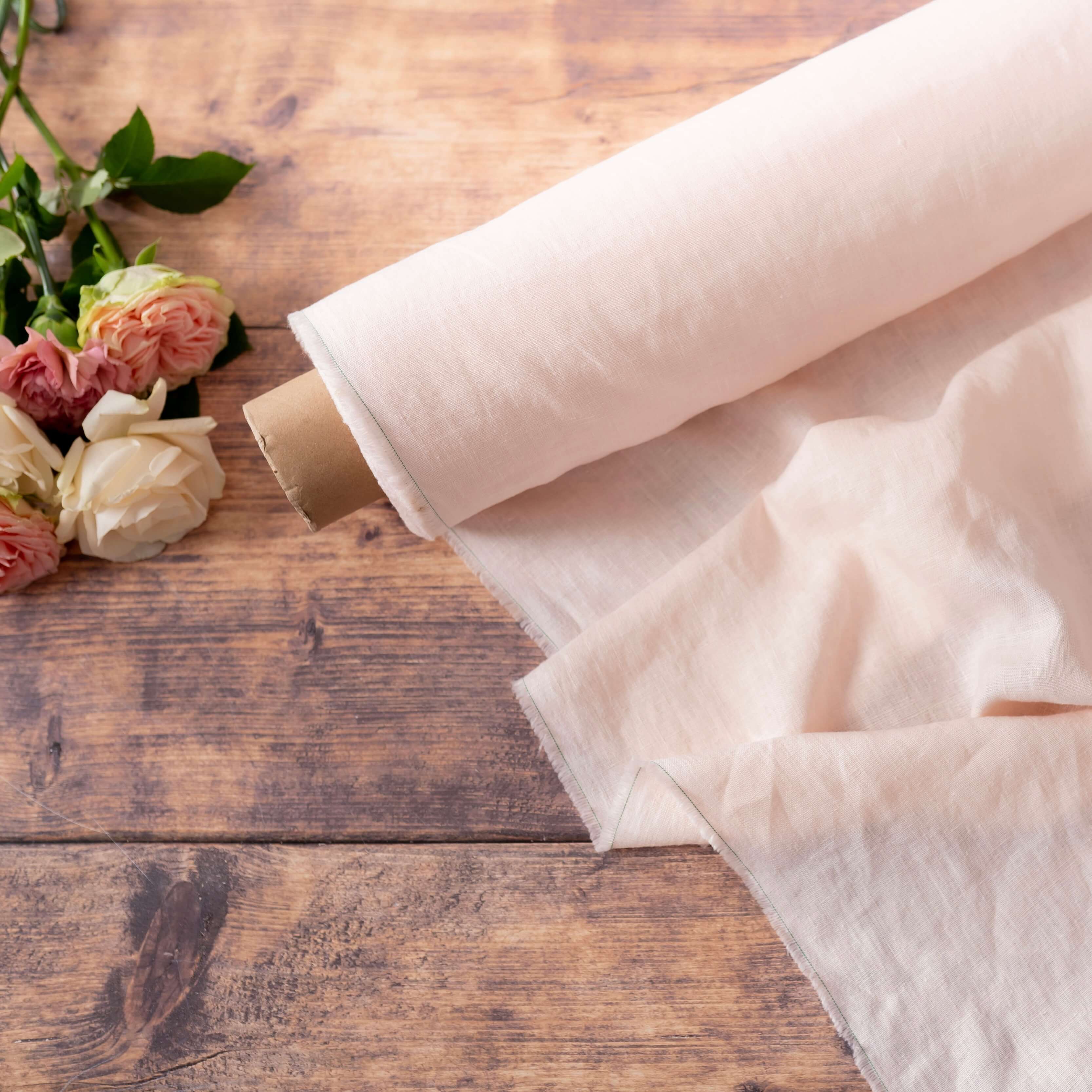 Pale Pink linen fabric, ready to cut, with scissors, thread bobbins and flowers